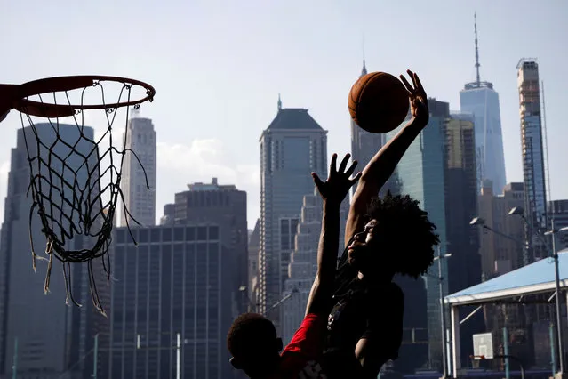Young men play basketball on a hot summer day in Brooklyn Bridge Park in the Brooklyn borough of New York City, U.S., August 10, 2020. (Photo by Brendan McDermid/Reuters)