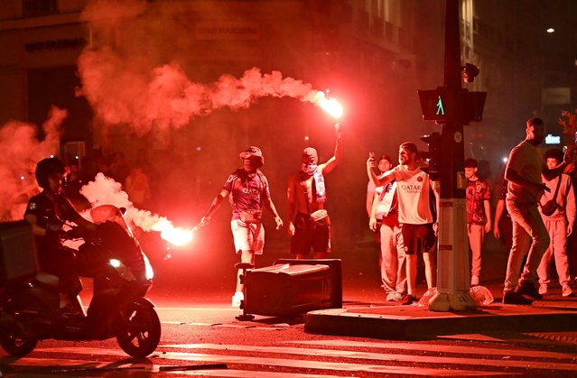Paris Saint-Germain (PSG) supporters gather holding flares on a street in Paris early June 1, 2025, during celebrations following their 5-0 victory in the UEFA Champions League final football match between Paris Saint-Germain (PSG) and Inter Milan held in Munich. (Photo by Lou Benoist/AFP Photo)