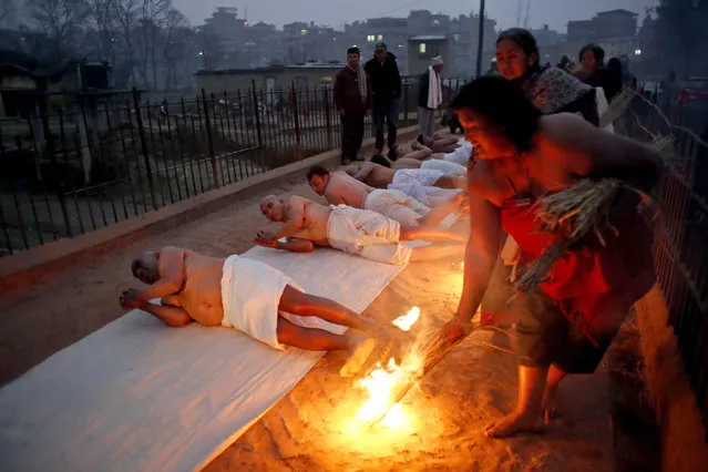 Nepalese Hindu devotees roll on the ground on the banks of Hanumante River on the last day of Madhav Narayan festival in Bhaktapur, Nepal, Wednesday, January 31, 2018. During the festival, devotees recite holy scriptures dedicated to Hindu goddess Swasthani and Lord Shiva. Unmarried women pray to get a good husband while those married pray for the longevity of their husbands by observing a month-long fast. (Photo by Niranjan Shrestha/AP Photo)