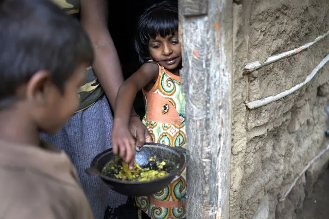 Sulochana Madushani, right, eats Okara curry from a pot at Mahadamana village in Dimbulagala, about 200 kilometres northeast of Colombo, Sri Lanka, Sunday, December 11, 2022. Due to Sri Lanka's current economic crisis families across the nation have been forced to cut back on food and other vital items because of shortages of money and high inflation. Many families say that they can barely manage one or two meals a day. (Photo by Eranga Jayawardena/AP Photo)