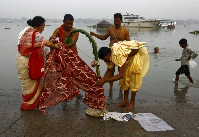 A Hindu priest (in yellow) helps a family to perform prayers in front of a banana tree trunk as part of a ritual on the banks of the Ganges river during Durga Puja festival in Kolkata, India, October 20, 2015. The Durga Puja festival, which is the biggest religious event for Bengali Hindus, is celebrated from October 19 to 22. Hindus believe that the goddess Durga symbolises power and the triumph of good over evil. (Photo by Rupak De Chowdhuri/Reuters)