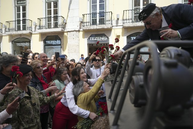Celeste Caeiro, 90, hands red carnations to former army captain Manuel Correia Silva, in Lisbon, Thursday, April 25, 2024, during the reenactment of troops movements of fifty years ago, part of anniversary celebrations of the Carnation Revolution. (Photo by Ana Brigida/AP Photo)
