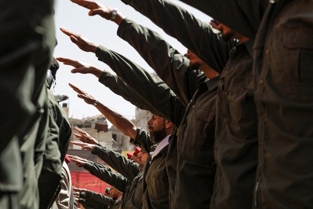 Palestinian members of a pro-Syrian government squad raise their arms in salute as they take part in a military parade to mark the annual Quds (Jerusalem) Day commemorations, in the Yarmouk refugee camp in Damascus on April 5, 2024. The Jerusalem Day, an initiative started by the late founder of the Islamic republic in Iran, is held annually on the last Friday of the Muslim fasting month of Ramadan, in support of the Palestinian people. (Photo by Louai Beshara/AFP Photo)