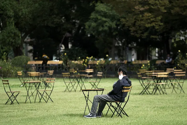 A man pulling off a protective mask rests at an open air cafe Monday, October 12, 2020, in Tokyo. The Japanese capital confirmed more than 70 coronavirus cases on Monday. (Photo by Eugene Hoshiko/AP Photo)