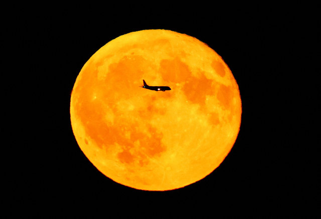 A passenger plane passes a full moon known as the “Sturgeon Moon” as the moon rises over Frankfurt, Germany on August 9, 2025. (Photo by Kai Pfaffenbach/Reuters)