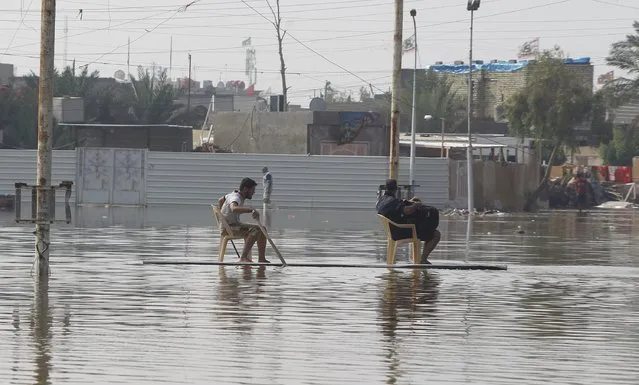 People use a board to travel on a flooded street after heavy rainfall in Baghdad, Iraq, October 31 2015. (Photo by Ahmed Saad/Reuters)
