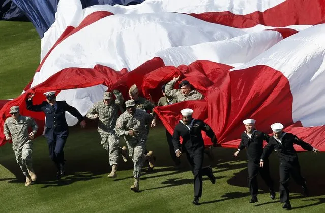 Members of the U.S. military run a large flag onto the field before the Philadelphia Phillies home opener against the Kansas City Royals in their MLB Interleague baseball game in Philadelphia, Pennsylvania, April 5, 2013. (Photo by Tim Shaffer/Reuters)