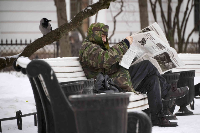 A man reads a newspaper in a park in St. Petersburg, Russia, Friday, February 17, 2023. (Photo by Dmitri Lovetsky/AP Photo)