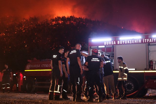 Firefighters attempt to extinguish a wildfire as smoke and flames rise from a forested area in the Gursu district of Bursa early on July 27, 2025. (Photo by Onur Yurtsever/AFP Phoot)