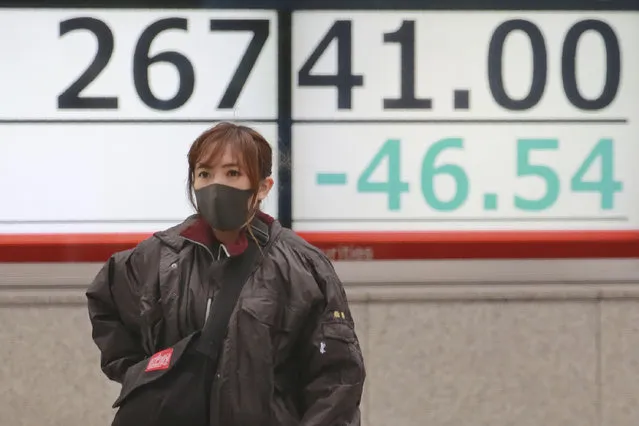 A woman walks by an electronic stock board of a securities firm in Tokyo, Wednesday, December 2, 2020. Asian markets are mixed after the U.S. benchmark S&P 500 set another record. (Photo by Koji Sasahara/AP Photo)