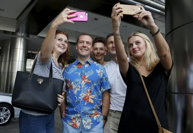Russian Prime Minister Dmitry Medvedev poses for pictures with tourists while sightseeing during his visit to Kuala Lumpur, Malaysia, for the East Asia Summit (EAS), November 22, 2015. (Photo by Dmitry Astakhov/Reuters/Sputnik)