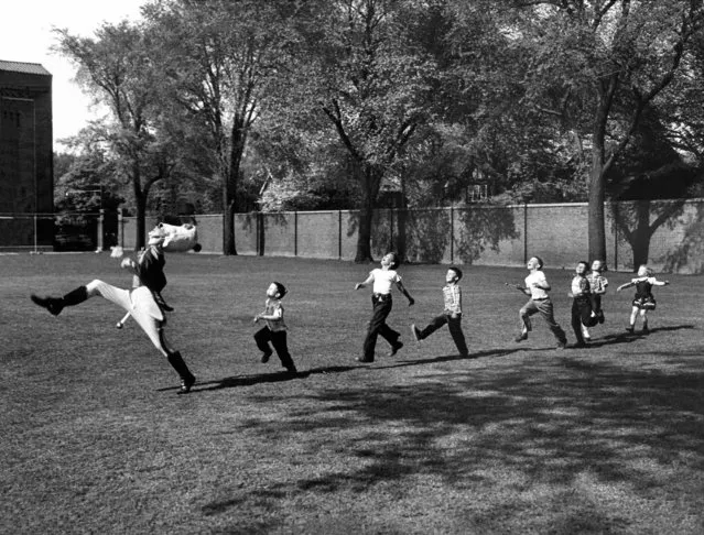 Uniformed drum major for the University of Michigan  marching band practicing his high-kicking prance as he leads a line of seven admiring children who are all trying to imitate his flamboyant technique while marching across the campus lawn, 1950. (Photo by Alfred Eisenstaedt/Time & Life Pictures)