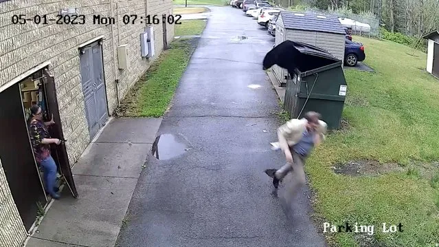 Principal of an elementary school runs away as a black bear jumps out from the dumpster, in Summersville, West Virginia, U.S., May 1, 2023 in this still image obtained from a social media video. (Photo by Nicholas County Board Of Education via Reuters)