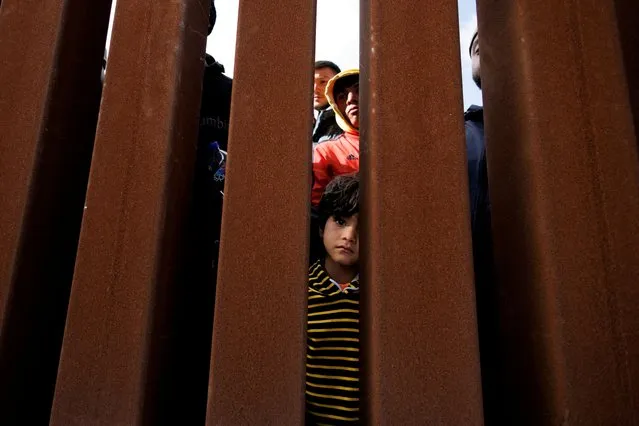 A young boy peers through the border wall as migrants gather between primary and secondary border fences in San Diego as the United States prepares to lift COVID-19-era restrictions known as Title 42, that have blocked migrants at the U.S.- Mexico border from seeking asylum since 2020, near San Diego, California, U.S., May 8, 2023. (Photo by Mike Blake/Reuters)
