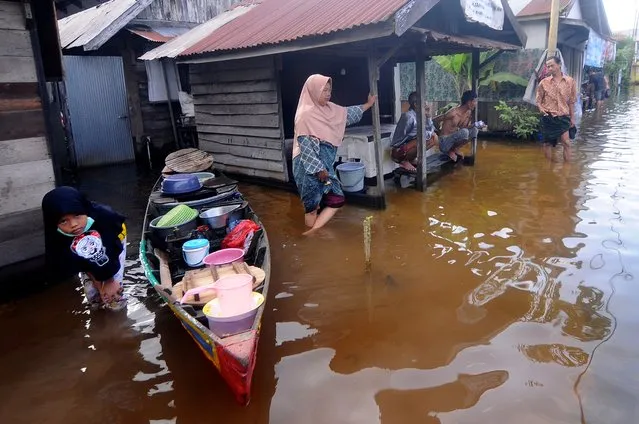 People talk outside their homes at a neighborhood affected by flood in Banjarmasin, South Kalimantan on Borneo Island, Indonesia, Sunday, January 17, 2021. many thousands of people have been evacuated and a number have been killed in recent days in flooding on Indonesia's Borneo island, officials said Sunday. (Photo by Iman Satria/AP Photo)
