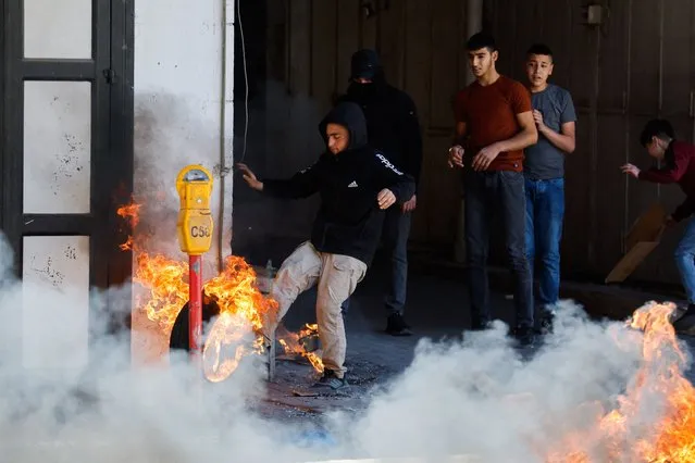 A Palestinian kicks a burning tire during clashes between Palestinians and Israeli soldiers following the death of Palestinian prisoner Khader Adnan during a hunger strike in an Israeli jail, in Hebron in the Israeli-occupied West Bank on May 2,2023. (Photo by Mussa Issa Qawasma/Reuters)