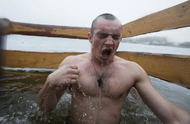 A man crosses himself as he dips into the icy waters of a lake as part of celebrations for Epiphany, near the village of Pilnitsa, northeast of Minsk January 19, 2015. Orthodox believers marked Epiphany on January 19 by immersing themselves in icy waters regardless of the weather. (Photo by Vasily Fedosenko/Reuters)