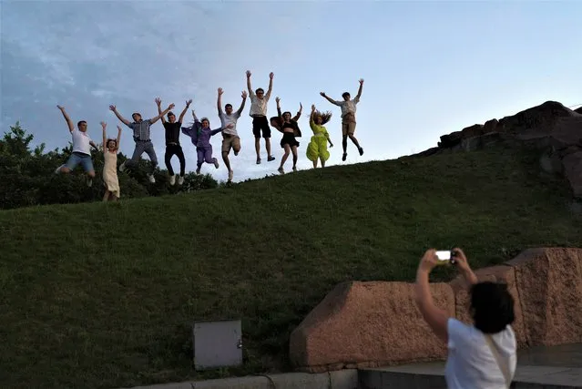 A group of recent high school grads leap as they pose for photos to celebrate their graduation in Kyiv, Ukraine, Monday, July 3, 2023. (Photo by Jae C. Hong/AP Photo)