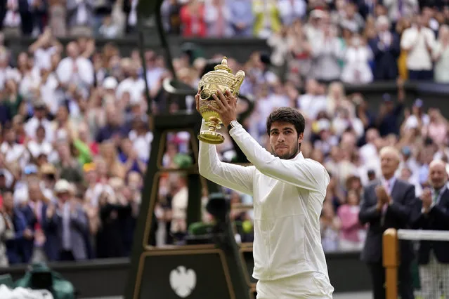 Spain's Carlos Alcaraz celebrates with his trophy after beating Serbia's Novak Djokovic in the men's singles final on day fourteen of the Wimbledon tennis championships in London, Sunday, July 16, 2023. (Photo by Alberto Pezzali/AP Photo)