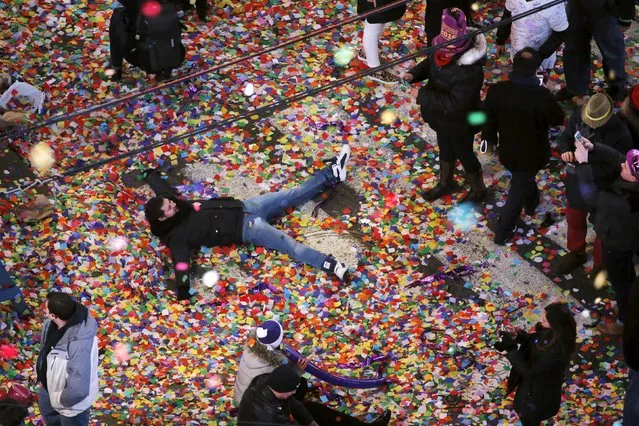 A reveler plays in confetti on the streets during New Year's festivities inside Times Square in New York January 1, 2016. (Photo by Lucas Jackson/Reuters)