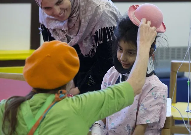 Belgian clown Rondelle adjusts the hat of Zeinab from Lebanon at the pediatric department of the Hopital Erasme at the Universite Libre de Bruxelles (ULB), in Brussels January 20, 2015. (Photo by Yves Herman/Reuters)