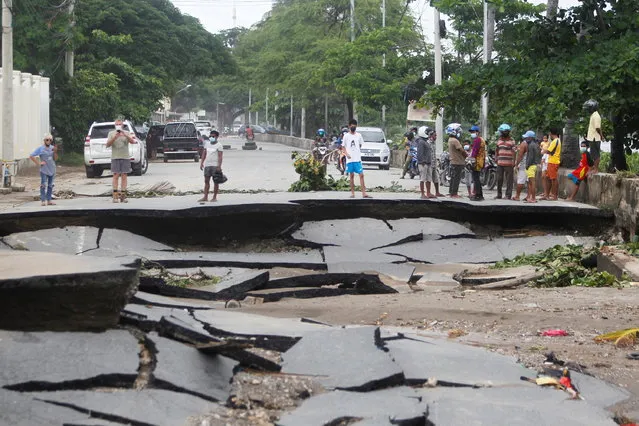 People stand near roads damaged by floods after heavy rainfall in Dili, East Timor, April 5, 2021. (Photo by Lirio da Fonseca/Reuters)