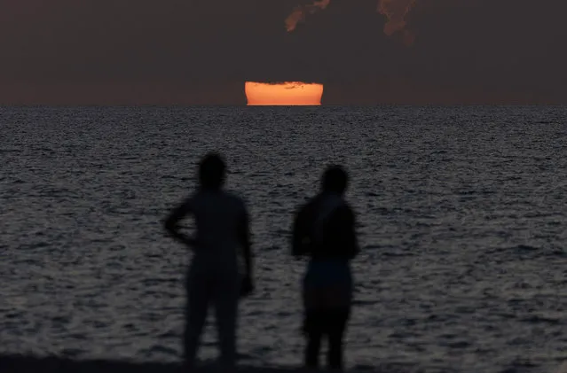 People enjoy the sunrising over the Atlantic Ocean on July 13, 2023 in Miami Beach, Florida. With triple-digit heat indices over South Florida, the surface ocean temperatures are 92 to 96 degrees Fahrenheit, the warmer coastal ocean water is threatening Florida's coral reefs, and could create stronger tropical storms and hurricanes. (Photo by Joe Raedle/Getty Images)