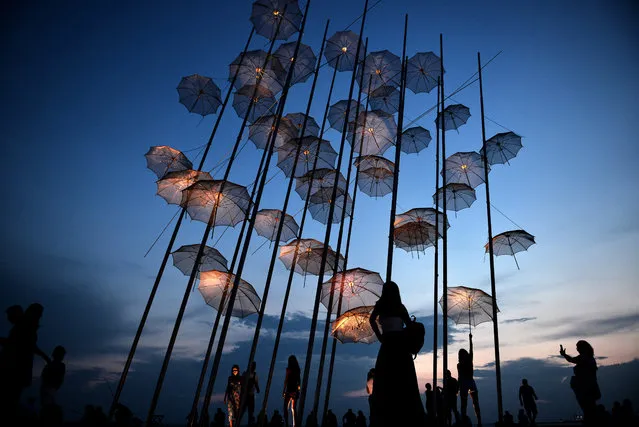 People take photos under the “Umbrellas” sculpture by Greek sculptor George Zongolopoulos on the new waterfront in Thessaloniki on August 26, 2018. The sea has always been an integral part of Thessaloniki's attraction, both as a commercial waterway that has sustained its economy and as a privilege that few seafront cities have showcased to such advantage. The city's orientation toward the sea is due to a great extent to the vision of Ernest Hebrard, the French urban planner and architect tasked with redesigning the center after the devastating fire of 1917.This rationale is instantly apparent along the waterfront, the 5k stretch from the port to the concert hall. Along this route, you can become immersed in the city's vibe in under an hour, with views of the sea and Mount OlympusThe old waterfront running along Nikis Avenue from the port to the White Tower. Walking along the Old Waterfront with the sea to your right, you will see a stretch of apartment blocks on your left. Most of these were built in the 1970s, though a handful of eclectic-style edifices from the early 20th century are also squashed among them.  It has served as a parade ground for kings and a place of protest for indignant citizens past and present. The New Waterfront of Thessaloniki, an ambitious renovation designed on 2013,  is a linear place with limited depth and great length, with the characteristics of a “front”, a thin layer inserted in the limit between land and sea. The project consists of a long walk along the waterfront and 13 green spaces. (Photo by Sakis Mitrolidis/AFP Photo)