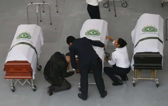 Funeral employees wrap an identification label around a casket covered in a white sheet with a Chapecoense soccer team logo that contains the remains of a team member at the San Vicente funeral home in Medellin, Colombia, Friday, December 2, 2016. The bodies of the Brazilian victims of this week's air tragedy will be repatriated later Friday on three flights to Chapeco, the hometown of the Brazilian soccer team. Members of the team and a group of journalists who perished on the flight were headed to the Copa Sudamericana finals when the plane ran out of fuel, crashing into the Andes outside Medellin. (Photo by Fernando Vergara/AP Photo)