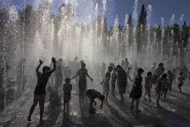 Ultra-Orthodox Jewish children along with other youngsters cool off during the summer heat, in a water fountain in Jerusalem on August 2, 2023. (Photo by Menahem Kahana/AFP Photo)