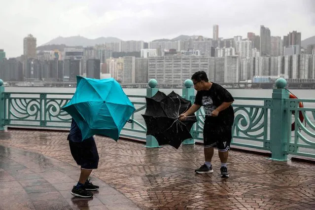 People struggle with their umbrellas in high winds brought by Super Typhoon Saola next to Victoria harbour in Hong Kong on September 1, 2023. Super Typhoon Saola threatened southern China on September 1 with some of the strongest winds the region has endured, forcing the megacities of Hong Kong and Shenzhen to effectively shut down. (Photo by Isaac Lawrence/AFP Photo)