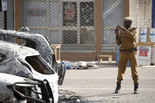 A Burkinabe soldier takes pictures of burned-out cars in front of the Splendid Hotel in Ouagadougou, Burkina Faso, January 17, 2016, a day after security forces retook the hotel from al Qaeda fighters who seized it in an assault. (Photo by Joe Penney/Reuters)