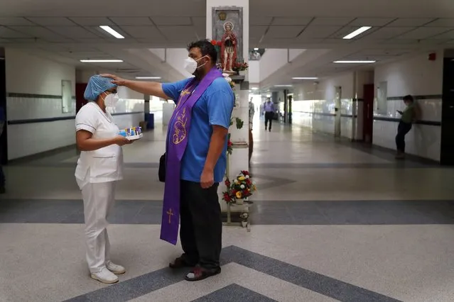 Catholic priest Juan Carlos Ayala blesses a nurse at the Clinicas Hospital in San Lorenzo, Paraguay, Monday, May 17, 2021. Ayala is a Franciscan Order priest that walks along the hospital's corridors blessing workers and the relatives of COVID-19 patients. (Photo by Jorge Saenz/AP Photo)