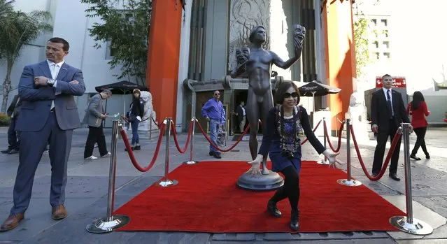 A person poses in front of a 10-foot embodiment of the Screen Actors Guild Awards Actor statuette in the forecourt of the TCL Chinese theatre in Hollywood, California January 26, 2016. The statue is one of five created in the likeness of the 12-inch tall, 16-pound solid bronze Actor statuette, which this year's 22nd Annual Screen Actors Guild Awards honorees will receive for outstanding performances. (Photo by Mario Anzuoni/Reuters)
