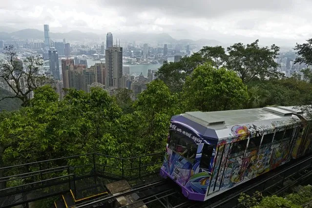 A Peak Tram passes an uphill of the Victoria Peak with a backdrop of Hong Kong on June 17, 2021. (Photo by Vincent Yu/AP Photo)