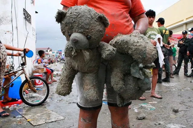 A survivor carries her daughter's stuffed teddy bears near Tacloban on Tuesday. (Photo by Jeoffrey Maitem/Getty Images)