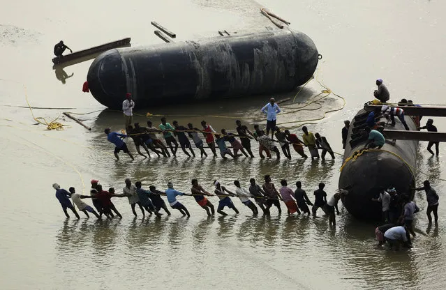 Indian laborers pull a pontoon buoy with a rope in the river Ganges as they build a floating pontoon bridge over the river Ganges for the upcoming Kumbh Mela festival, in Allahabad, India, Wednesday, November 28, 2018. Millions of Hindu pilgrims are expected to take part in the large religious congregation on the banks of Sangam during the Mahakumbh festival in January. (Photo by Rajesh Kumar Singh/AP Photo)