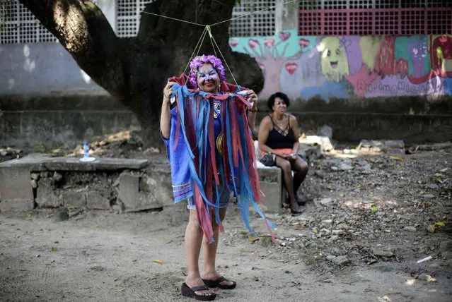 A patient from the Nise de Silveira mental health institute stands in costume during the institute's carnival parade, called in Portuguese: “Loucura Suburbana”, or Suburban Madness, in the streets of Rio de Janeiro, Brazil, Thursday, February 4, 2016. Patients, their relatives and workers from the institute held their parade one day before the official start of Carnival. (Photo by Silvia Izquierdo/AP Photo)