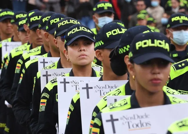 Police officers hold pictures of colleagues killed by criminal gangs during a tribute in Bogota, Colombia on July 28, 2022. About 36 policemen have been killed allegedly by criminal gangs trying to exhibit its strength in the face of a possible negotiation with the next government. (Photo by Daniel Munoz/AFP Photo)