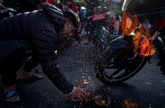 A man breaks a coconut as he performs Hindu rituals for his vehicle on the ninth day of Dashain festival in Kathmandu, Nepal, Monday, October 23, 2023. The festival commemorates the slaying of a demon king by Hindu goddess Durga, marking the victory of good over evil. (Photo by Niranjan Shrestha/AP Photo)