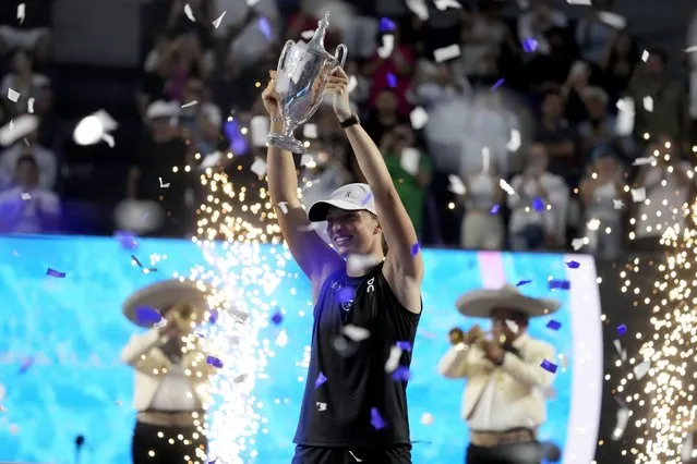 Iga Swiatek, of Poland, holds up her trophy after her victory over Jessica Pegula, of the United States, in the women's singles final of the WTA Finals tennis championships, in Cancun, Mexico, Monday, November 6, 2023. (Photo by Fernando Llano/AP Photo)