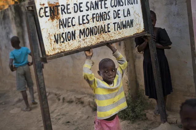 A child plays under a sign reading, “health center built with funding from Taiwan World Vision Funds” at the Mama Wa Mapendo clinic in Lubumbashi, Democratic Republic of the Congo on Tuesday, August 14, 2018. An Associated Press investigation focused in Congo's second city, the copper-mining metropolis of Lubumbashi, discovered that of more than 20 hospitals and clinics visited, all but one detain patients unable to pay their bills. The practice is illegal according to the Congolese penal code. (Photo by Jerome Delay/AP Photo)