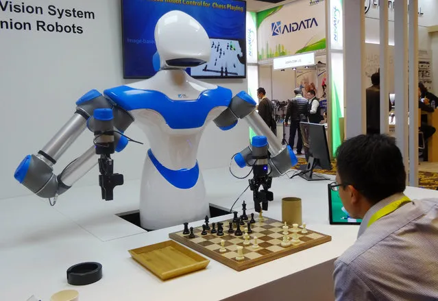 A robot developed by Taiwan engineers moves chess pieces on a board against an opponent, at the 2017 Consumer Electronic Show (CES) in Las Vegas, Nevada on January 8, 2017. The robot developed by Taiwan's Industrial Technology Research Institute, which spent the week playing games against opponents at the Consumer Electronics Show, was displaying what developers call an “intelligent vision system” which can see its environment and act with greater precision than its peers. (Photo by Rob Lever/AFP Photo)