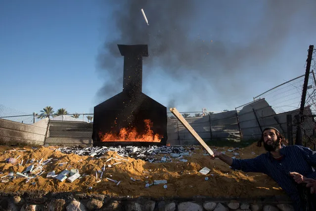 Orthodox Jews throw candles into a burning fire and pray outside the tomb of Rabbi Yisrael Abuhatzeira, known as the Baba Sali, in the southern Israeli town of Netivot, 10 January 2019. Thousands of people came to pay their respect to Baba Sali, or “The Father of Prayer” in Arabic, who was a leading Moroccan rabbi and mystic renowned for his alleged ability to work miracles through his prayers. His tomb in Netivot is a popular pilgrimage site. (Photo by Abir Sultan/EPA/EFE)