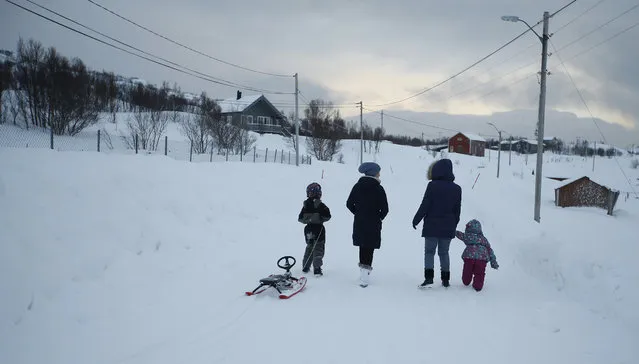 in this photo taken Tuesday, February 2, 2016, asylum seekers take their children fro a walk  near the temporary accommodation at  the Altnes camp on the island of Seiland, northern Norway. (Photo by Alastair Grant/AP Photo)