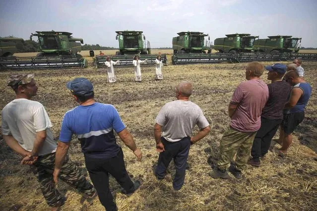 Artists perform for farmers during their break in harvest with their combines in the background in a wheat field near the village Tbilisskaya, Russia, Wednesday, July 21, 2021. Russia's Agricultural Ministry expects this year's grain harvest at 127 million metric tons. (Photo by Vitaly Timkiv/AP Photo)