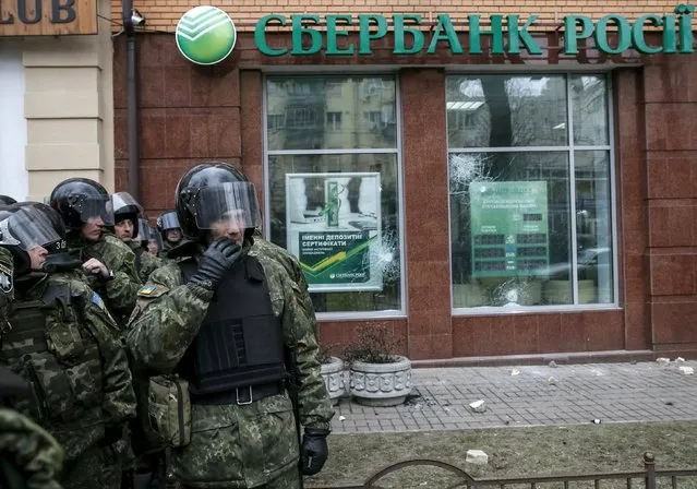 Interior Ministry security force members stand guard outside a branch of Russian bank Sberbank which was attacked during a protest against Russia in Kiev, Ukraine, February 20, 2016. (Photo by Gleb Garanich/Reuters)
