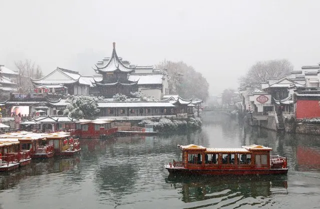 A boat cruises on a canal in the Confucius Temple Scenic Area during a snowfall in Nanjing, in China's eastern Jiangsu province on December 18, 2023. (Photo by AFP Photo/China Stringer Network)
