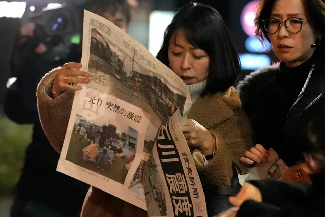People read extra edition of Yomiuri Shimbun newspaper reporting the earthquakes Monday, January 1, 2024 in Tokyo. Japan issued tsunami alerts and ordered evacuations following a series of earthquakes on Monday that started a fire and trapped people under rubble on the west coast of its main island. (Photo by Shuji Kajiyama/AP Photo)