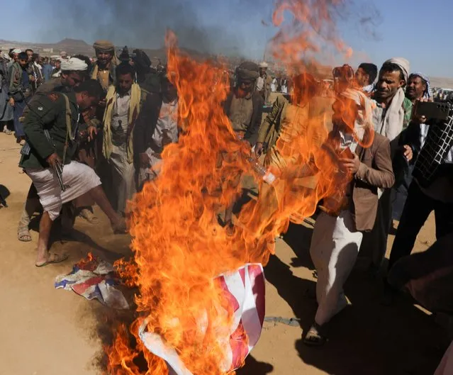 Tribal supporters of the Houthi group burn U.S. and British flags during a protest against recent U.S.-led strikes on Houthi targets, near Sanaa, Yemen on January 14, 2024. (Photo by Khaled Abdullah/Reuters)